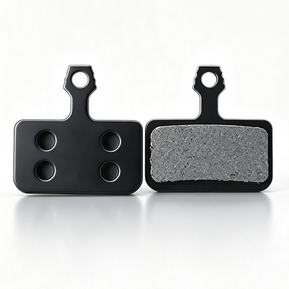  ZorixBike Ride Card Two black rectangular brake pads shown side by side on a clean white background, with one pad facing forward to show the textured gray friction surface and the other showing the back with four circular cutouts.